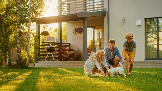 Image is of a family in their backyard playing with a puppy.
