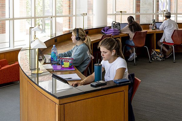 Four students studying in Hamon with laptops and notebooks.