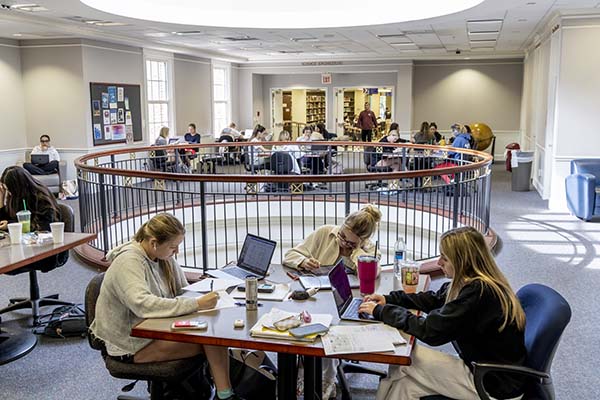 Students studying collaboratively in Fondren Library with laptops and notebooks on the table.