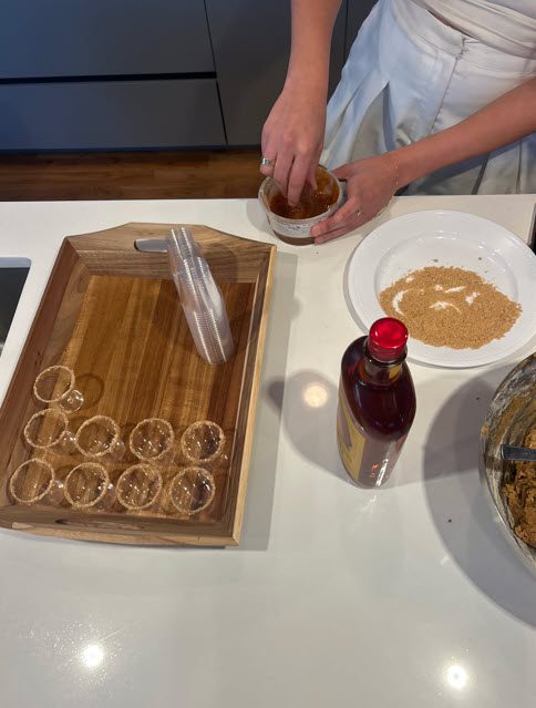 A wooden tray with plastic cups rimmed with sugar waiting to be filled.