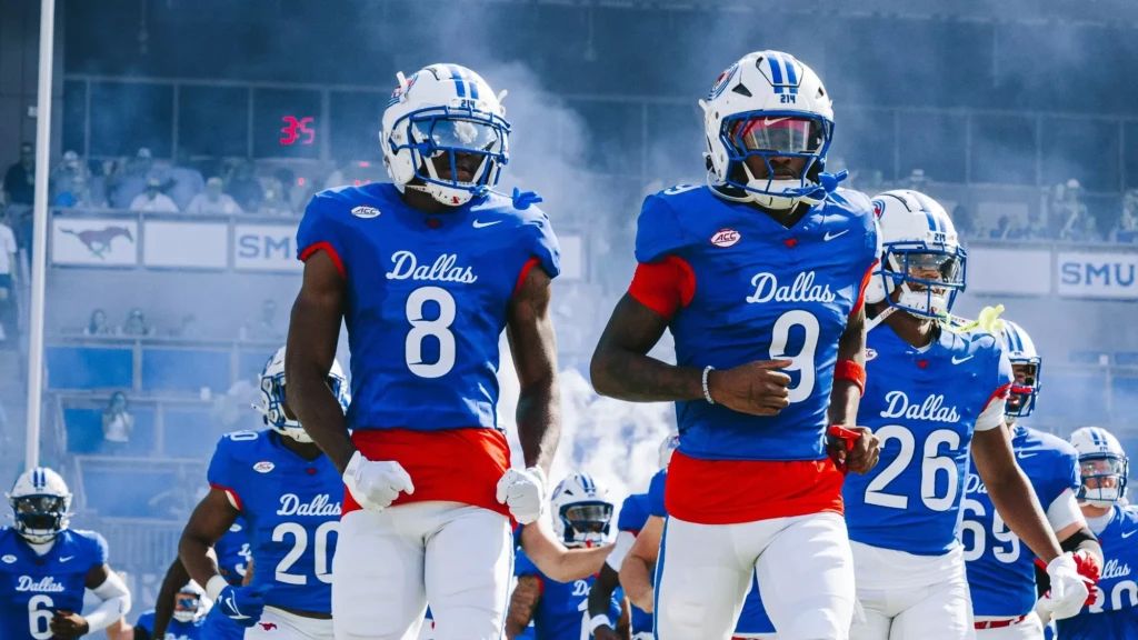 The SMU football team is entering the field with smoke in the background