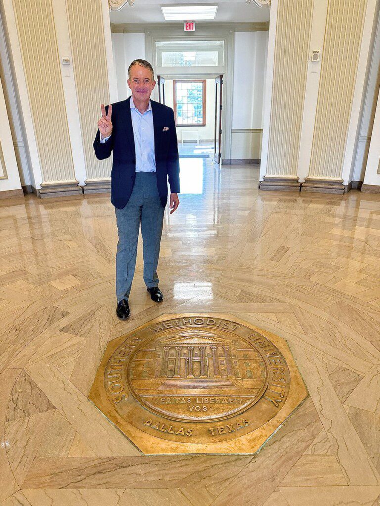 SMU President standing by Dallas Hall seal.